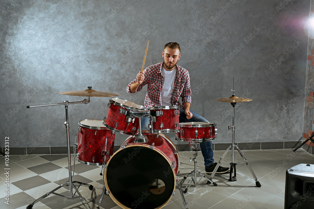 Fototapeta premium Musician playing the drums on brick wall background