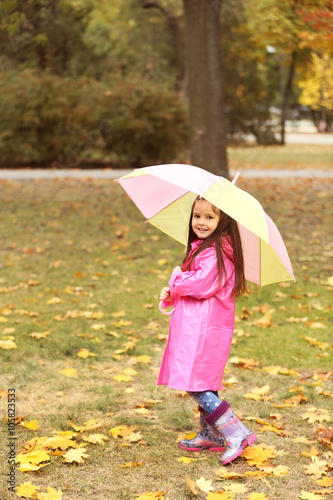 Beautiful little girl with umbrella in park