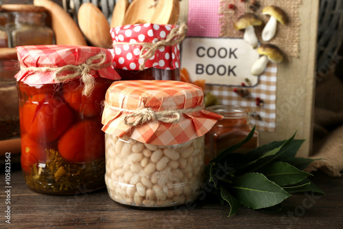 Fototapeta Naklejka Na Ścianę i Meble -  Jars with pickled vegetables, beans, spices and kitchenware on wooden background