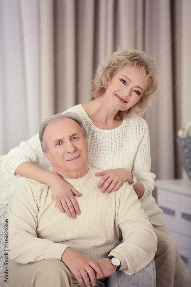 Happy mature couple sitting together on a sofa at home Happy mature couple sitting together on a sofa at home
