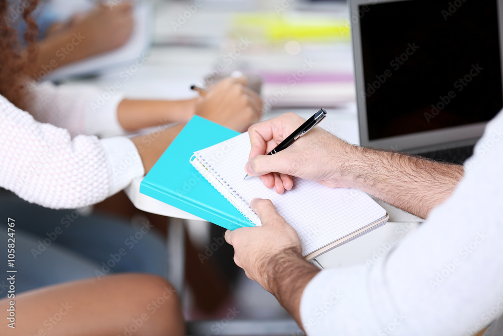 Fototapeta premium Young man sitting and making notes at the office meeting