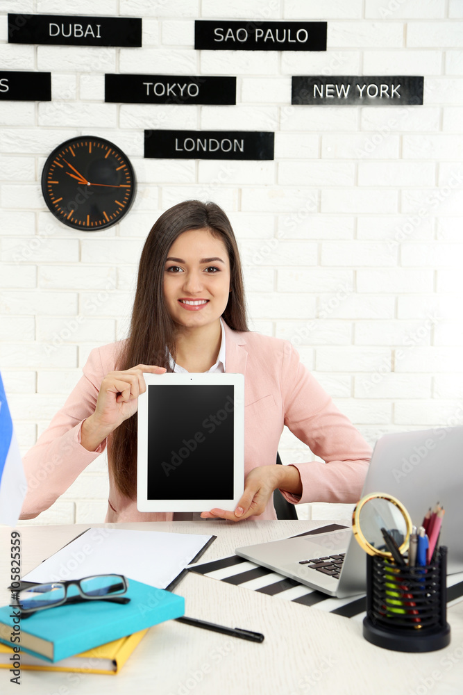 Young woman holding tablet in the office of travel company Young woman holding tablet in the office of travel company
