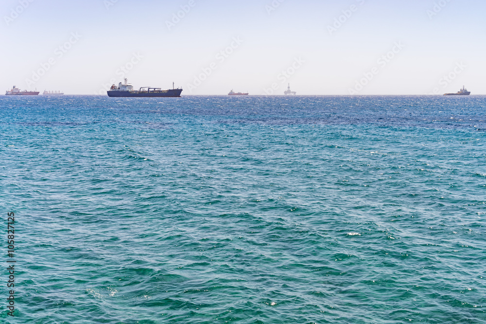 Mediterranean Sea with distant view on several ships and oil platform on horizon. Limassol, Cyprus.
