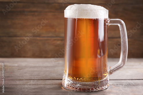 Glass mug of light beer on wooden table, close up