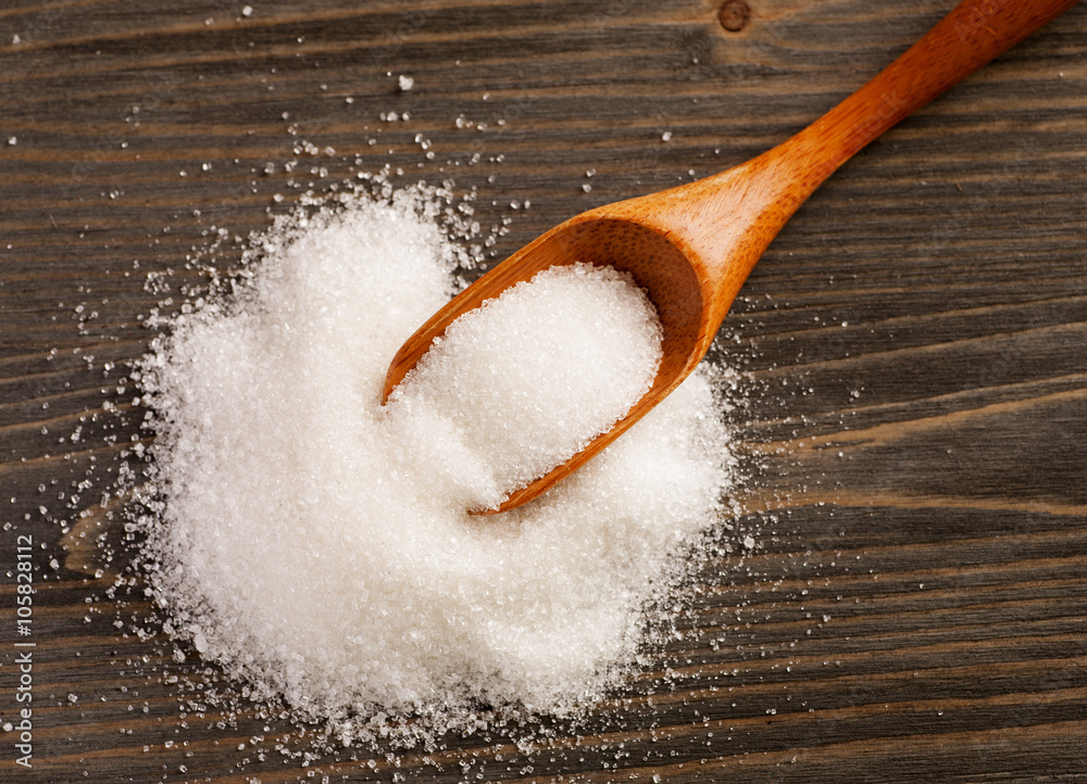 Spoon with sugar on a wooden table