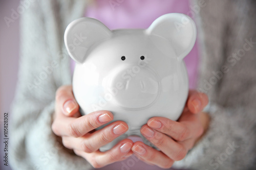 Woman holding in hands white piggy bank