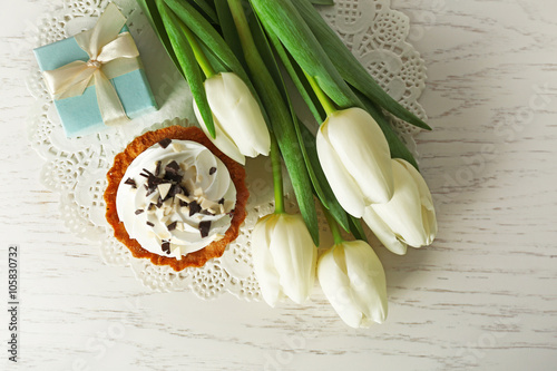 Fototapeta Naklejka Na Ścianę i Meble -  Bouquet of fresh tulips, cake and present box on wooden table, top view