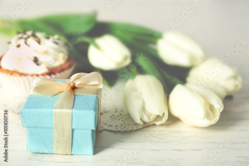 Bouquet of fresh tulips  cake and present box on wooden table closeup