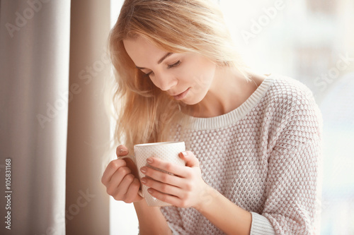 Woman holding a cup of coffee in her hands on the light background