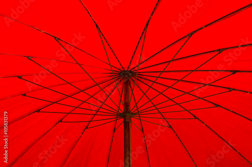 A red beach umbrella blocks out the hot, tropical sun.