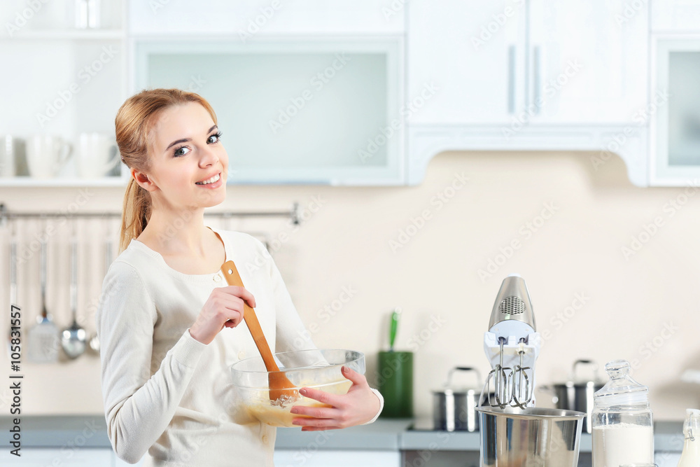 Young woman mixing dough in a bowl Young woman mixing dough in a bowl