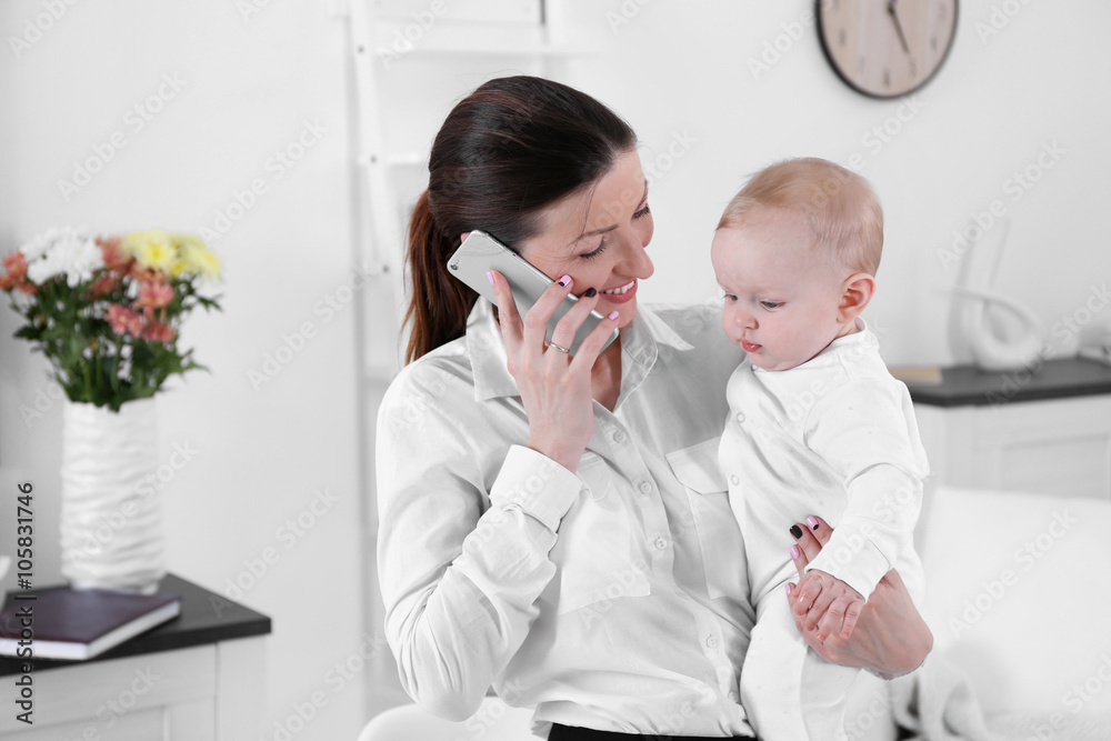 Businesswoman with baby boy working from home using mobile phone Businesswoman with baby boy working from home using mobile phone