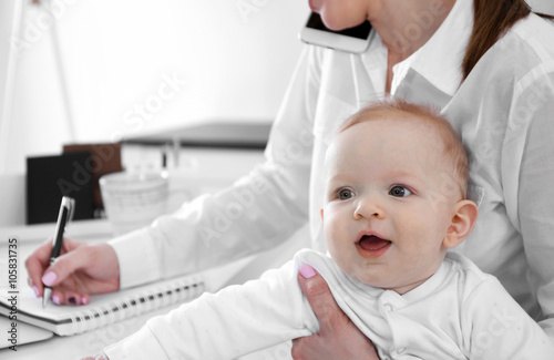 Cute baby boy on businesswoman's hands at home