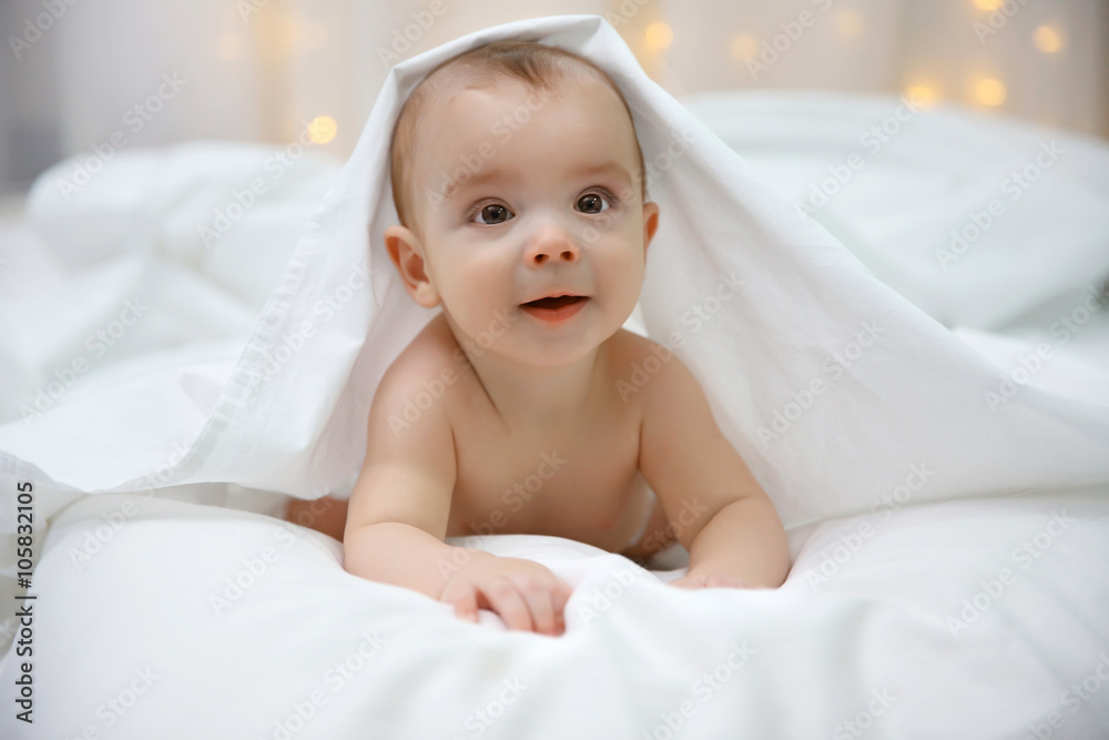 Naked adorable baby lying on soft bed, close up