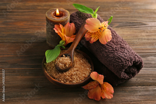 Spa set with sea salt, exotic flowers, candles and towel on wooden background photo