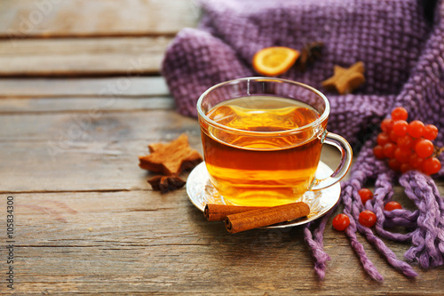 Glass cup of tea, purple blanket and herbs on wooden background