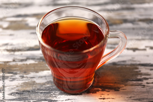 Glass cup of black tea on wooden table closeup