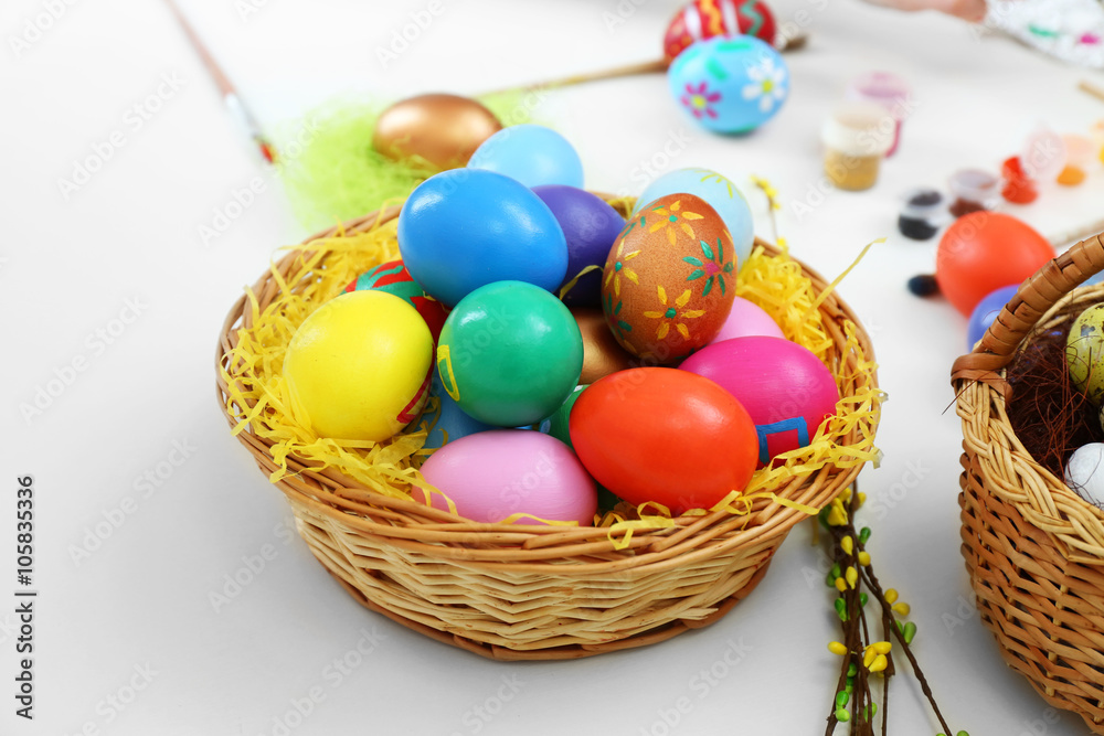 Colorful Easter eggs in wicker baskets on table closeup