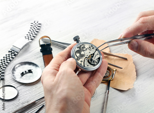 Watchmaker hands repairing mechanism of old watch closeup photo