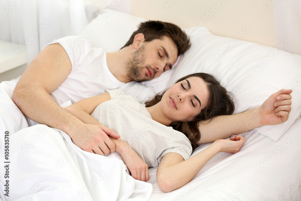 Young cute couple sleeping together in bed