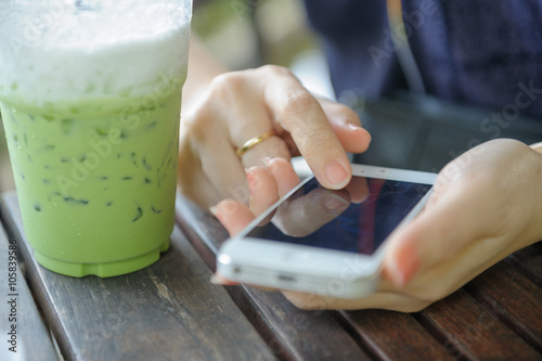 asian girl using smart phone with iced greentea photo