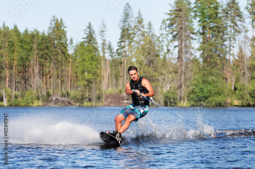 Valokuva Young man riding wakeboard on a summer lake