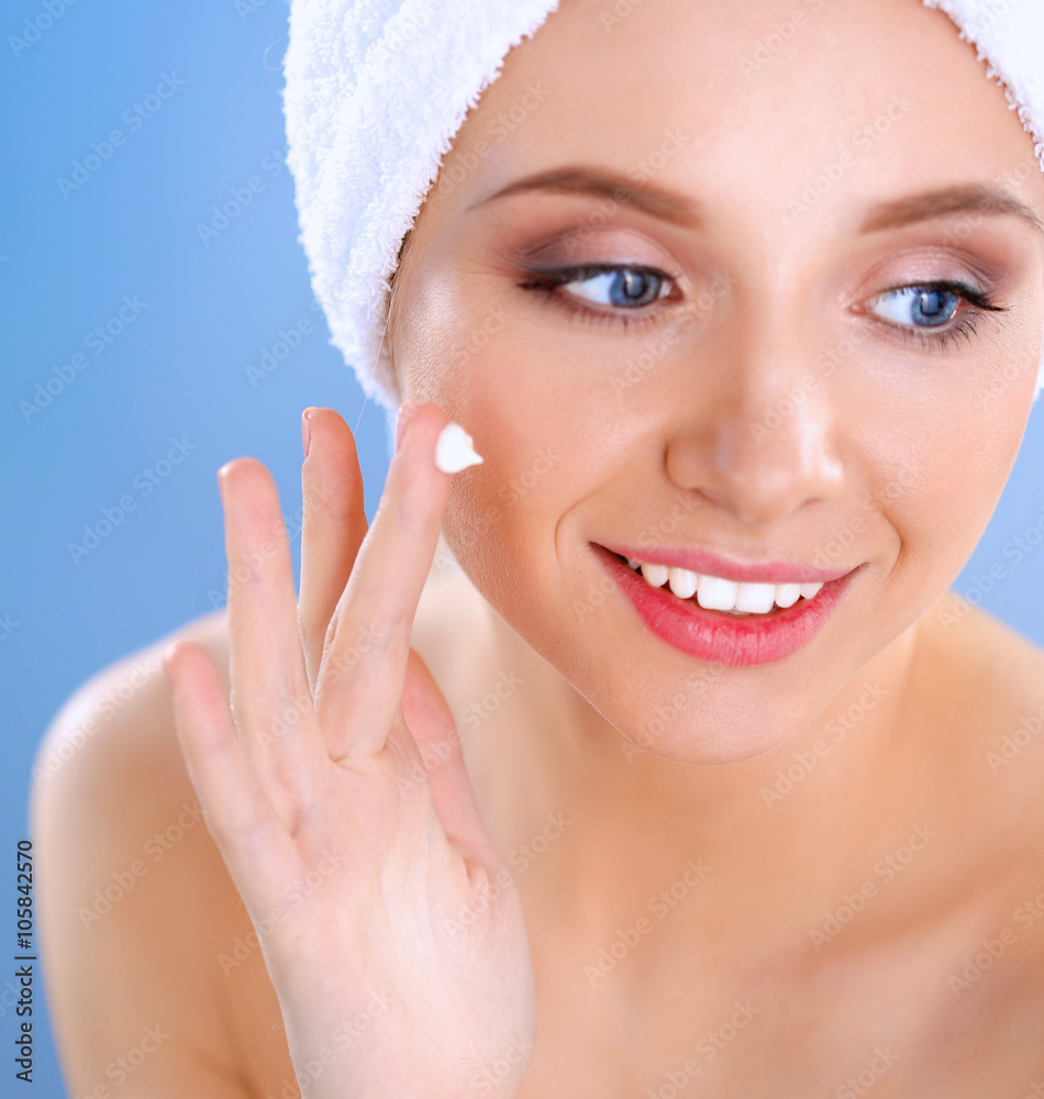 Beautiful young woman applying a creme on her face isolated on gray background Beautiful young woman applying a creme on her face isolated on gray background
