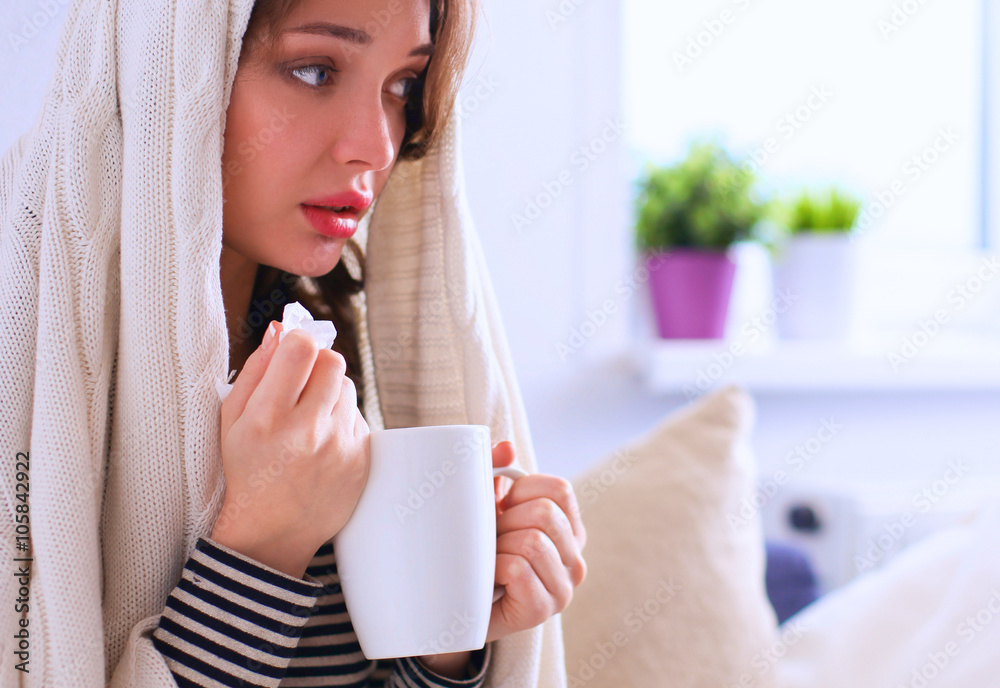 Portrait of a sick woman blowing her nose while sitting on the sofa Portrait of a sick woman blowing her nose while sitting on the sofa