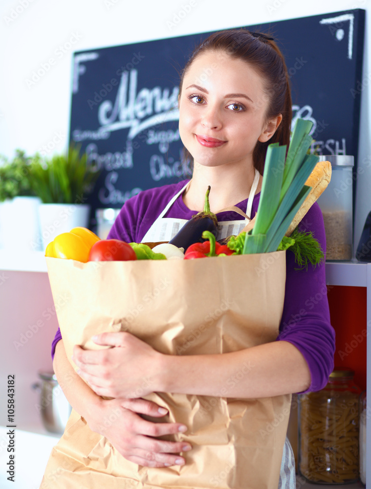 Young woman holding grocery shopping bag with vegetables Standing in the kitchen Young woman holding grocery shopping bag with vegetables Standing in the kitchen
