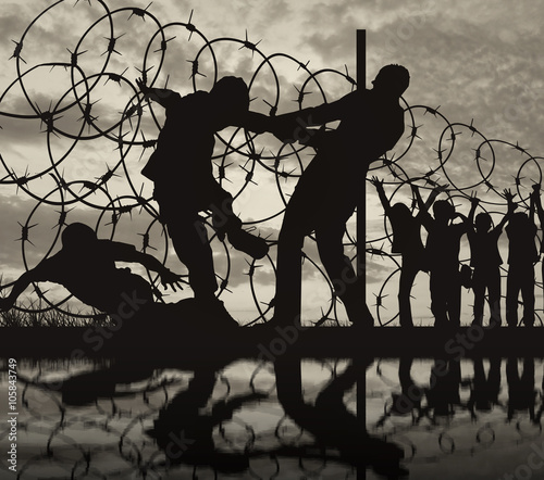 Schilderij op canvas Silhouette of refugees and barbed wire