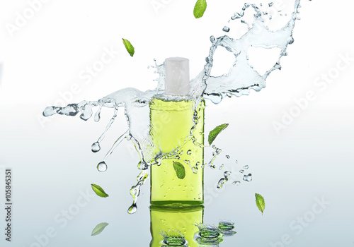 The herbal green moisturizing shampoo stands on the water background with splashes and mint leaves