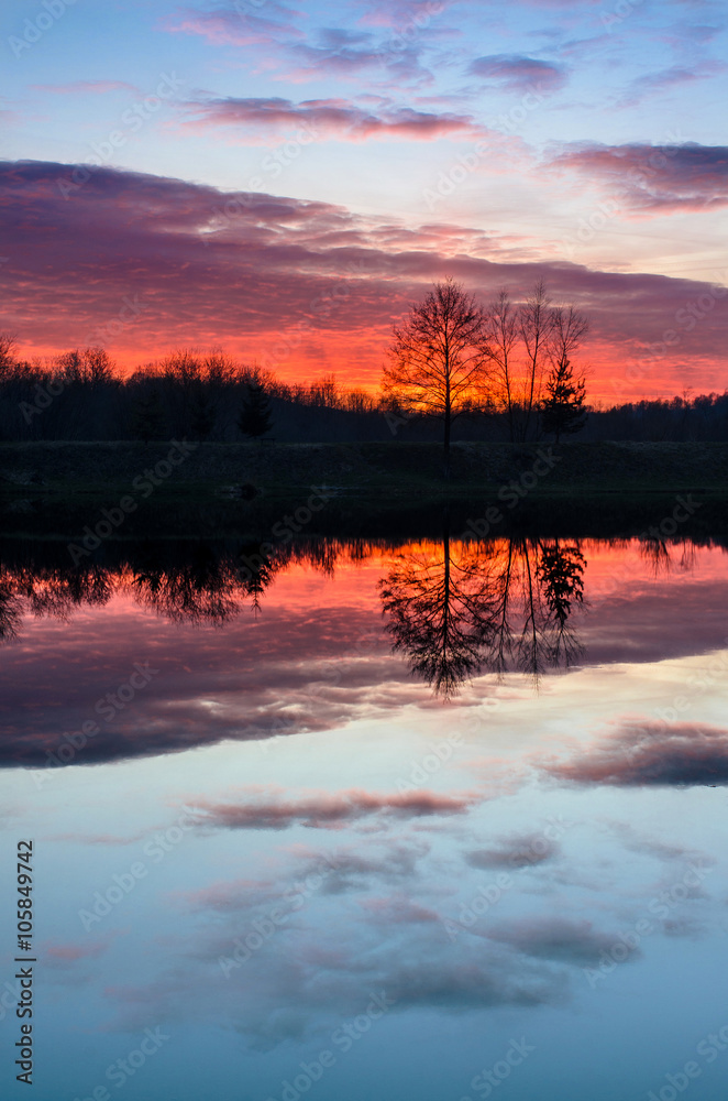 Beautiful sunset over the lake with colorful red sky and reflections in calm water