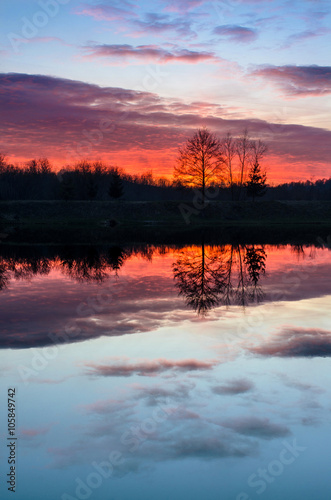 Beautiful sunset over the lake with colorful red sky and reflections in calm water