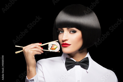 Woman with bob cut hair holding sushi with chopsticks