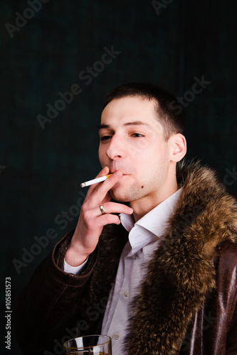 portrait of handsome man in fur coat with cigarette photo