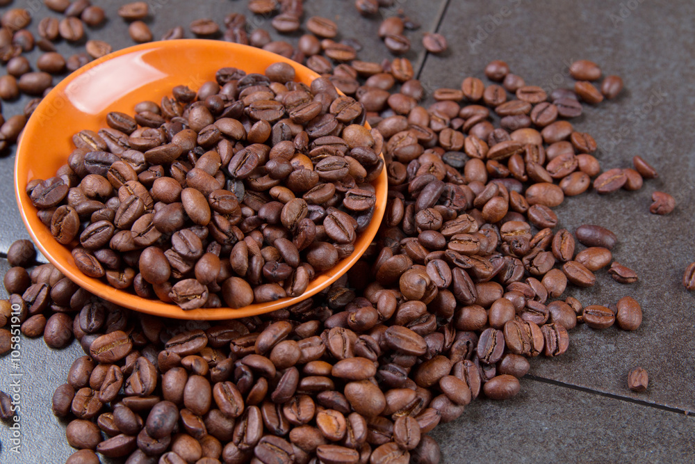 Fototapeta premium coffee beans in an orange plate on a dark stone background