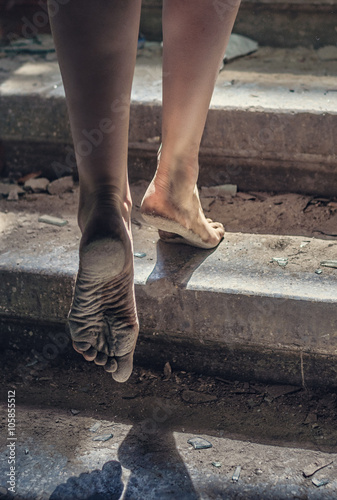 Barefoot girl climbs the stairs of a ruined house