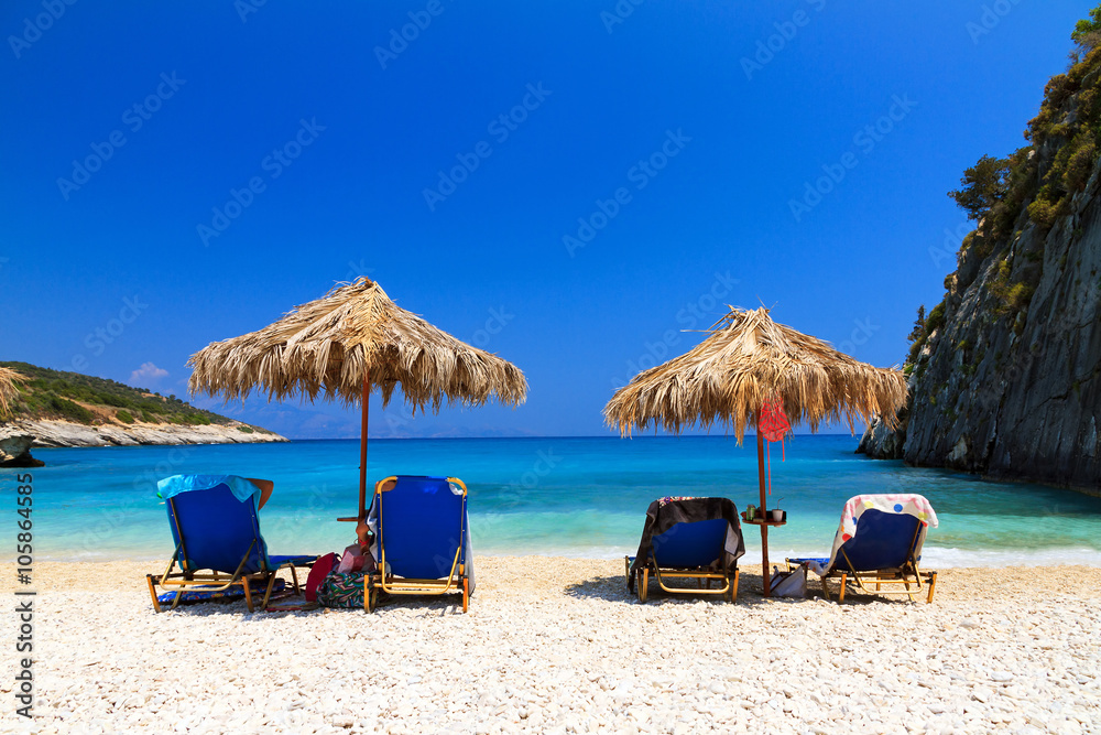 People are relaxing under a straw parasol on the beach at Xigia on the island of Zakynthos