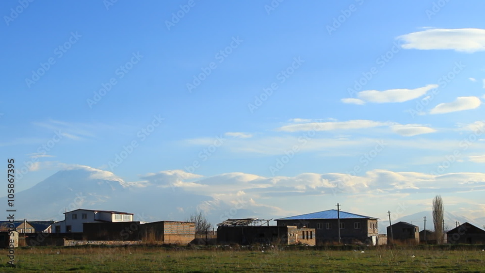 Timelapse of blue, gray clouds on background blue sky, houses and trees, countryside Timelapse of blue, gray clouds on background blue sky, houses and trees, countryside