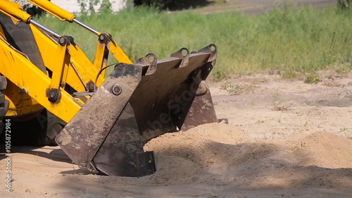 Yellow bulldozer rows sand in the bucket.