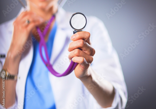 Female doctor with a stethoscope listening, isolated on grey background