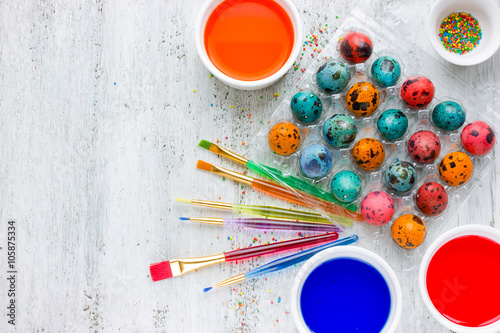 Painting Easter eggs process on white wooden background