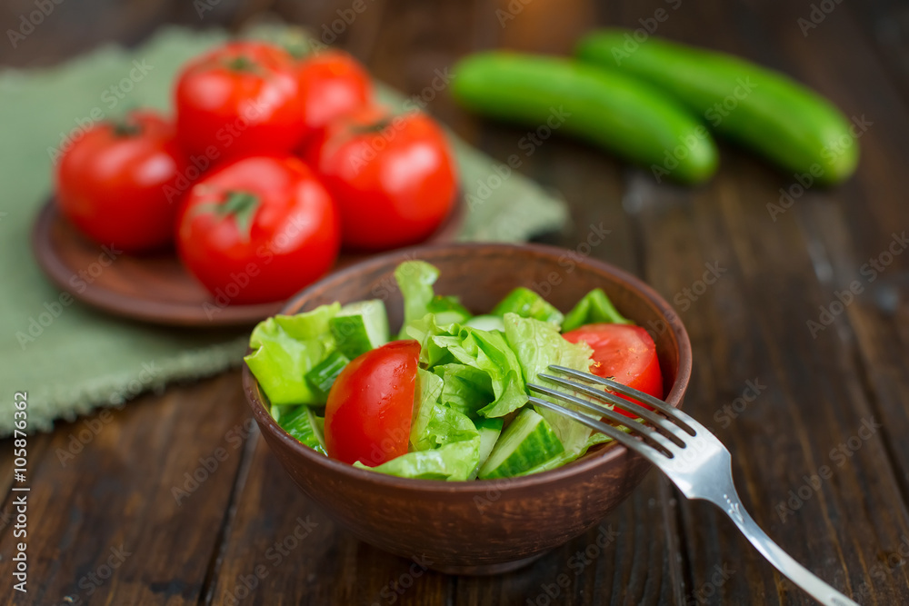 spring vegetables. tomatoes, cucumbers and lettuce on a wooden background spring vegetables. tomatoes, cucumbers and lettuce on a wooden background