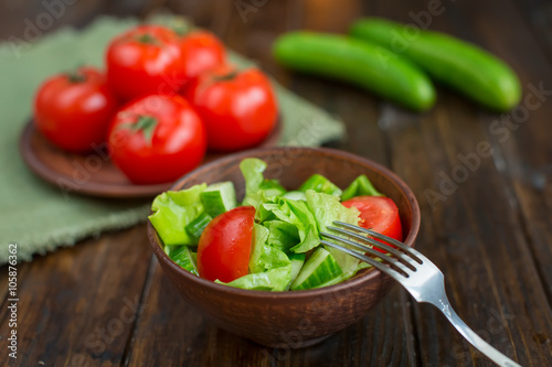 spring vegetables. tomatoes, cucumbers and lettuce on a wooden background