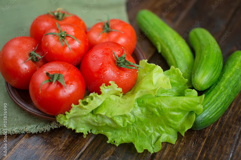 spring vegetables. tomatoes, cucumbers and lettuce on a wooden background spring vegetables. tomatoes, cucumbers and lettuce on a wooden background
