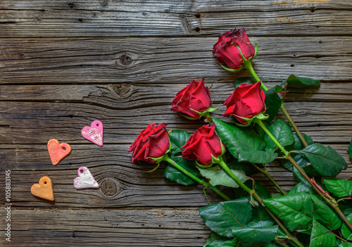 Roses and heart shapes over wooden background