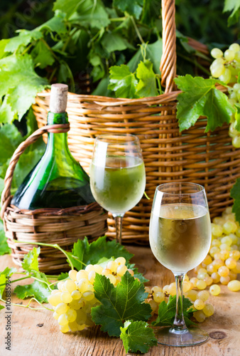 Two glasses of withe wine and basked with grape