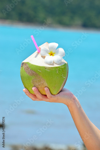  Coconut cocktails in woman hand against the turquoise sea