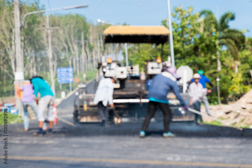 Worker operating asphalt paver machine during road construction