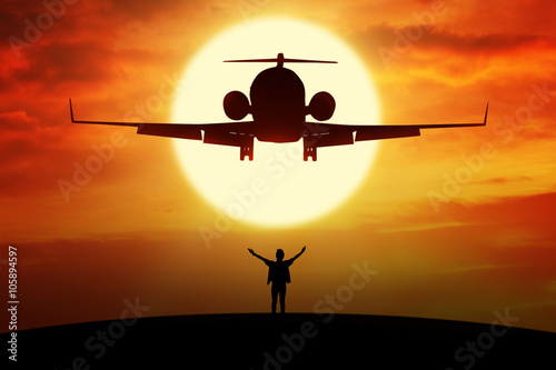 Man enjoy freedom on the hill under flying plane